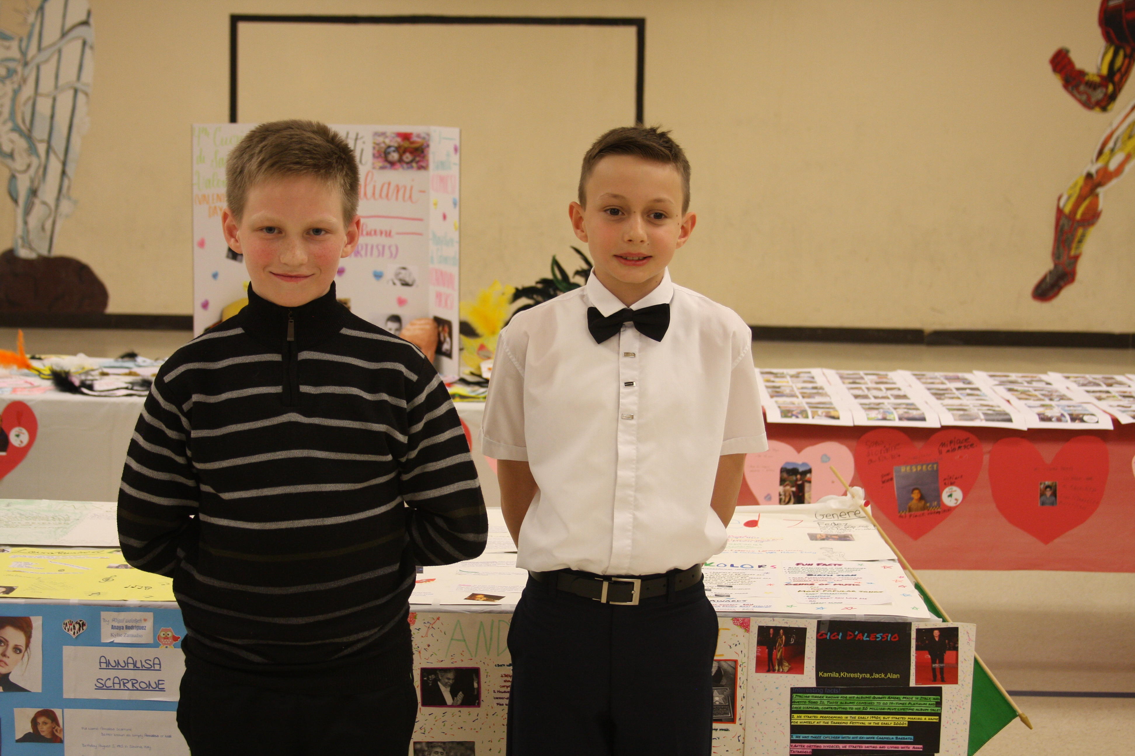 two boy posing in front of their art display
