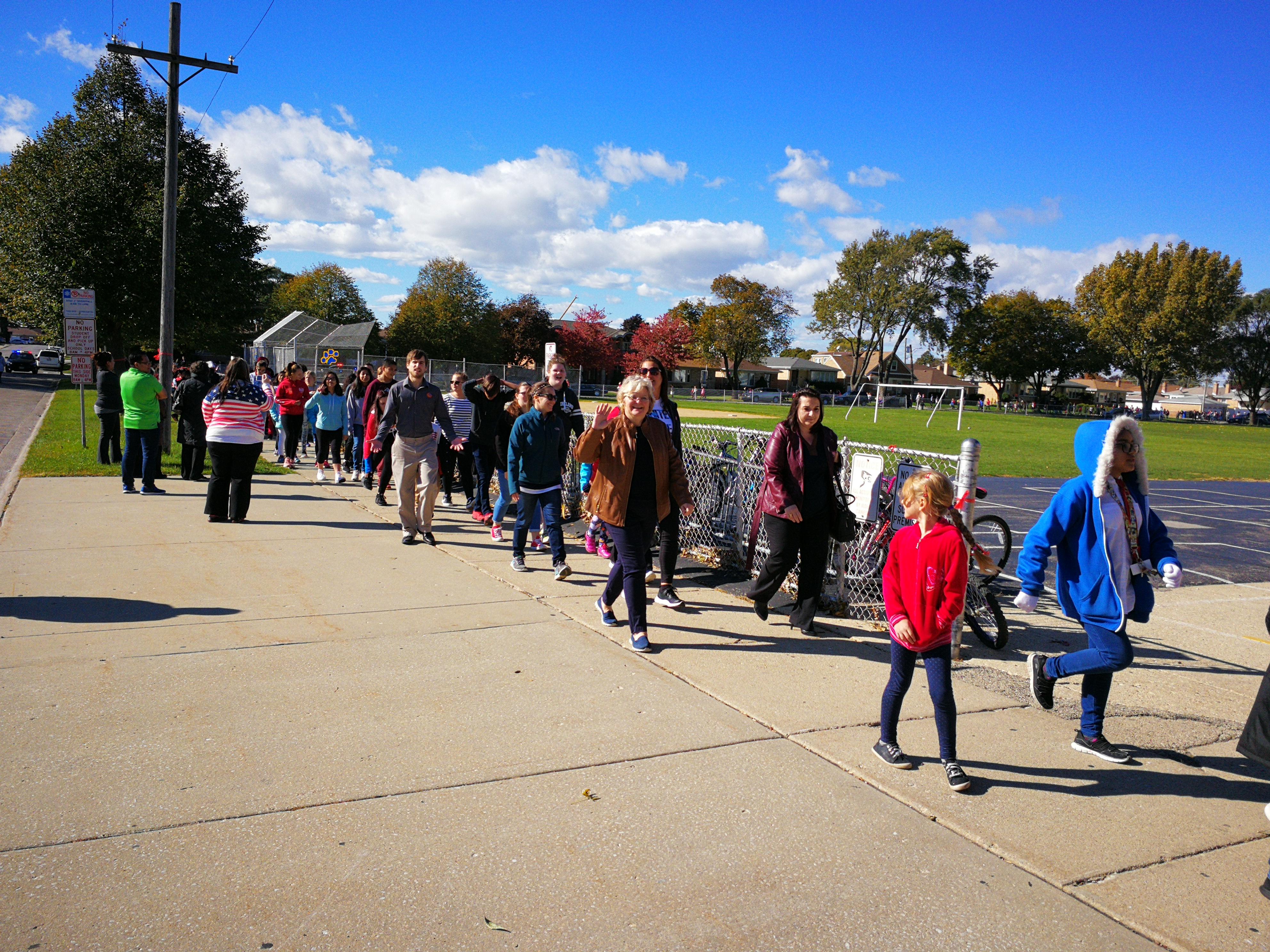 image of red ribbon walk, the Harwood Height Mayor walking united against drugs with Union Ridge School students, staff, and administrators