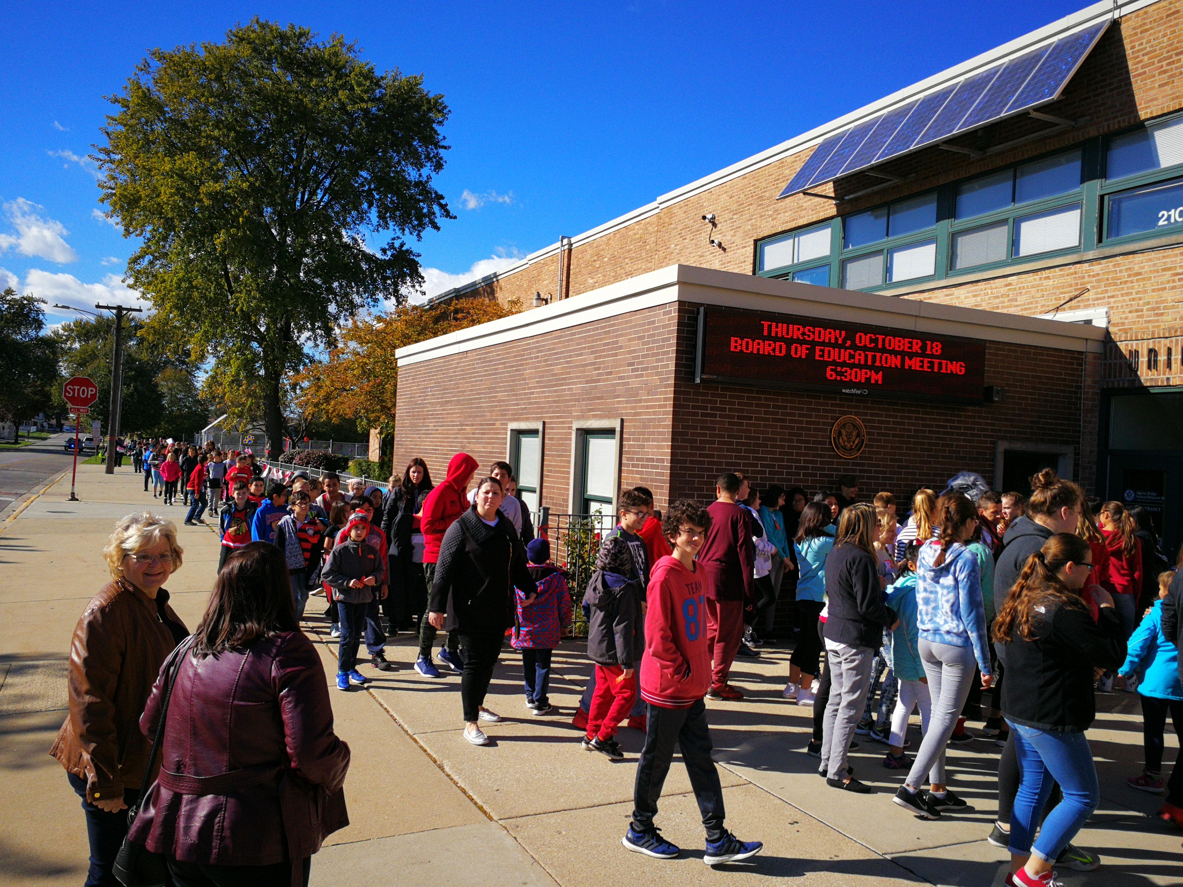 image of red ribbon walk, students entering the school building after the work