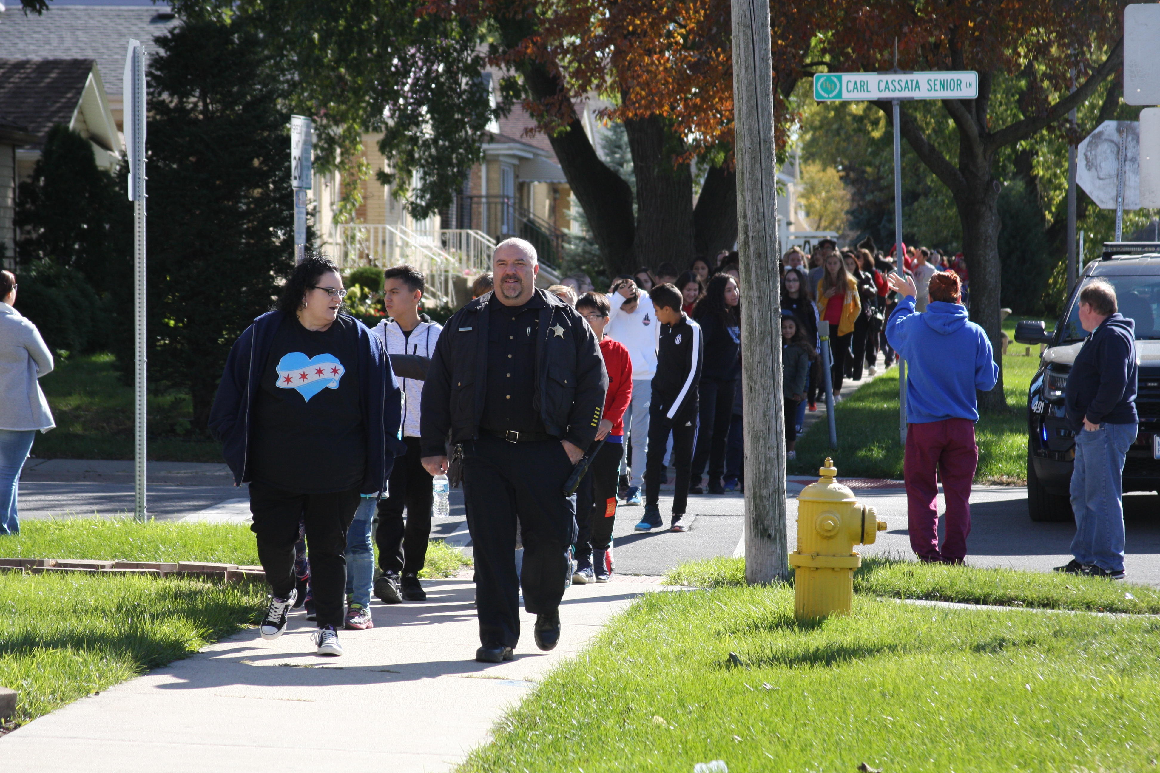 image of red ribbon walk, the Chief of Harwood Height police department leading the walk