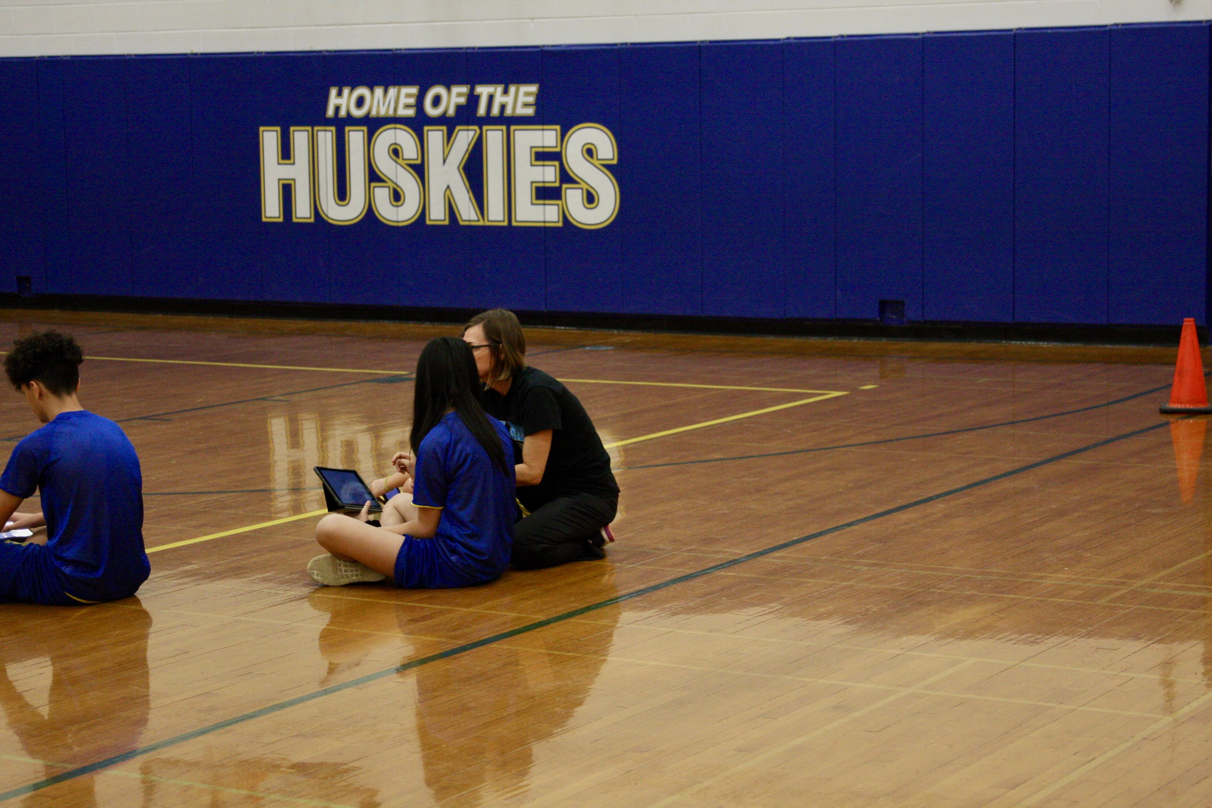 Science teacher working with student during PE class.