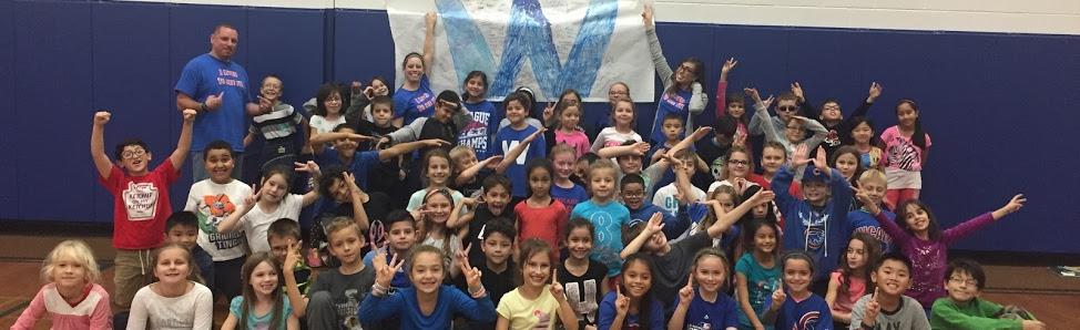 Third grade teachers and students posing with a Wrigley Flied W flag